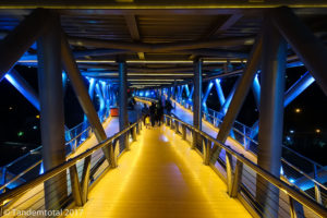 Dreistöckige Fußgängerbrücke mit Restaurants und Begrünung